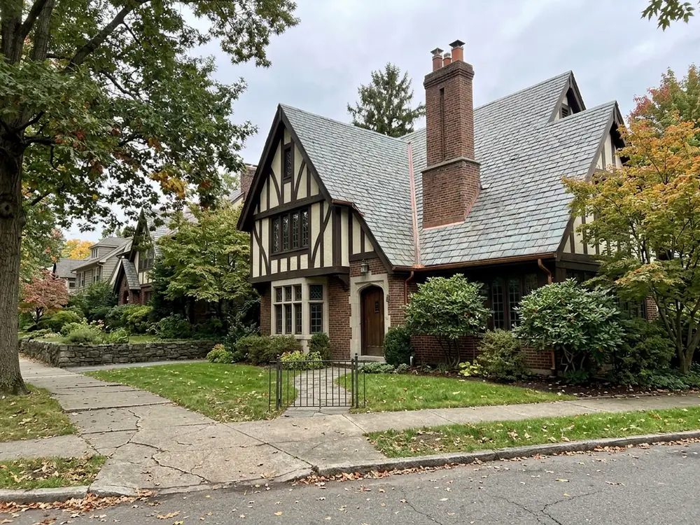 Tudor Revival house with steep gables, half-timbering and a grey-green slate roof with copper valley flashing